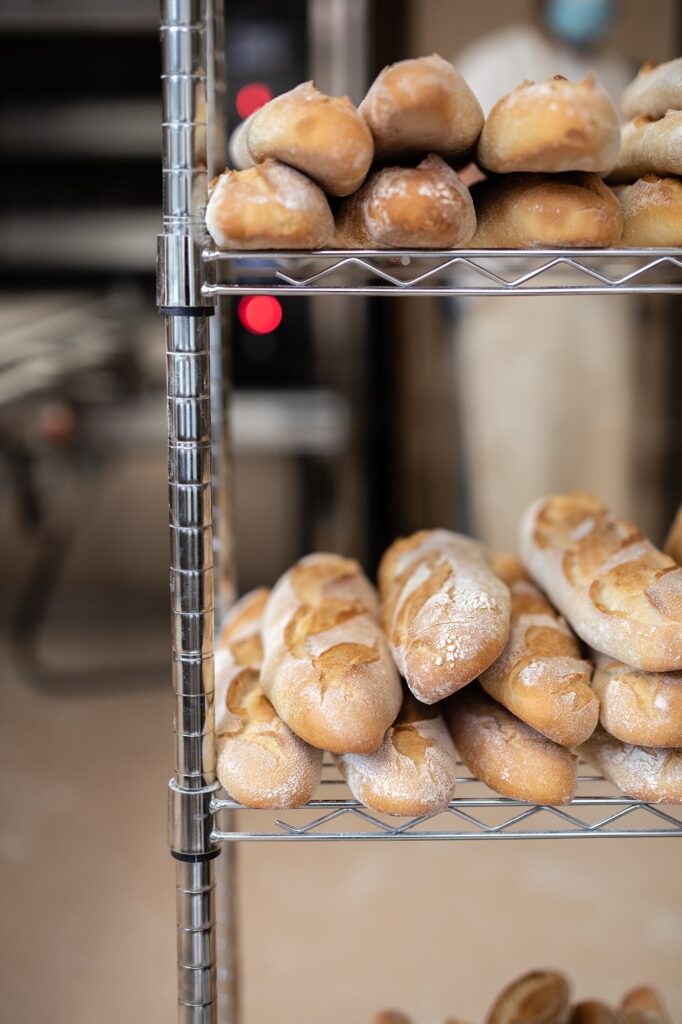 Barras de pan artesano colocadas en una estantería dentro de un obrador.