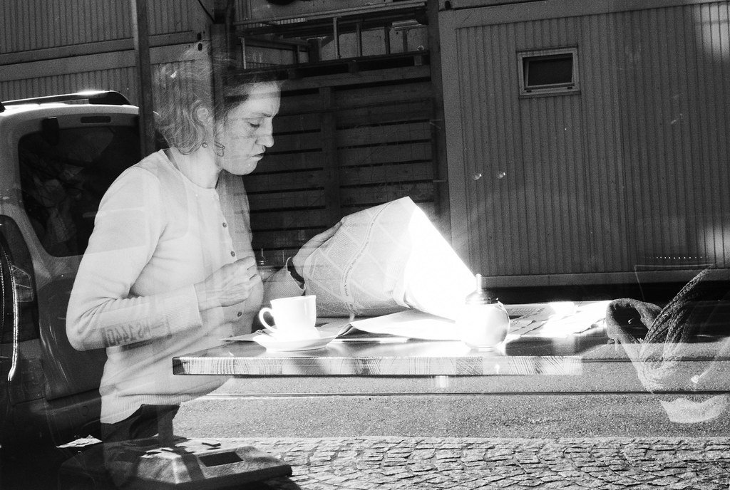 Persona leyendo el periódico en la mesa de un café