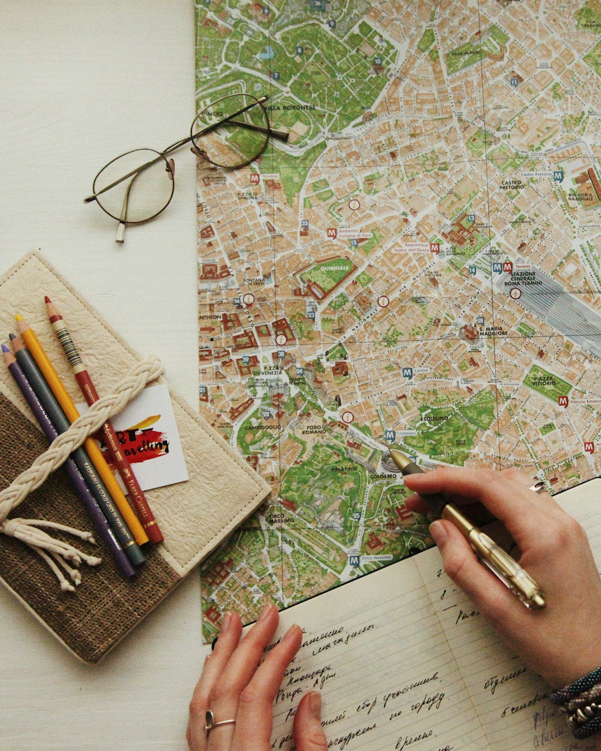 Manos escribiendo en un cuaderno de viaje sobre un mapa